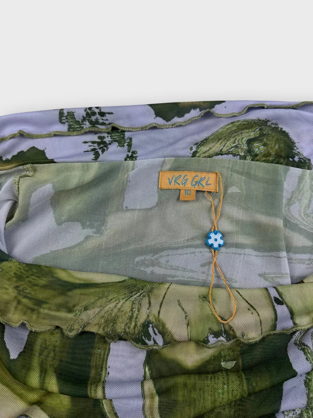 Detail view of long sleeve top in soft green abstract pattern.