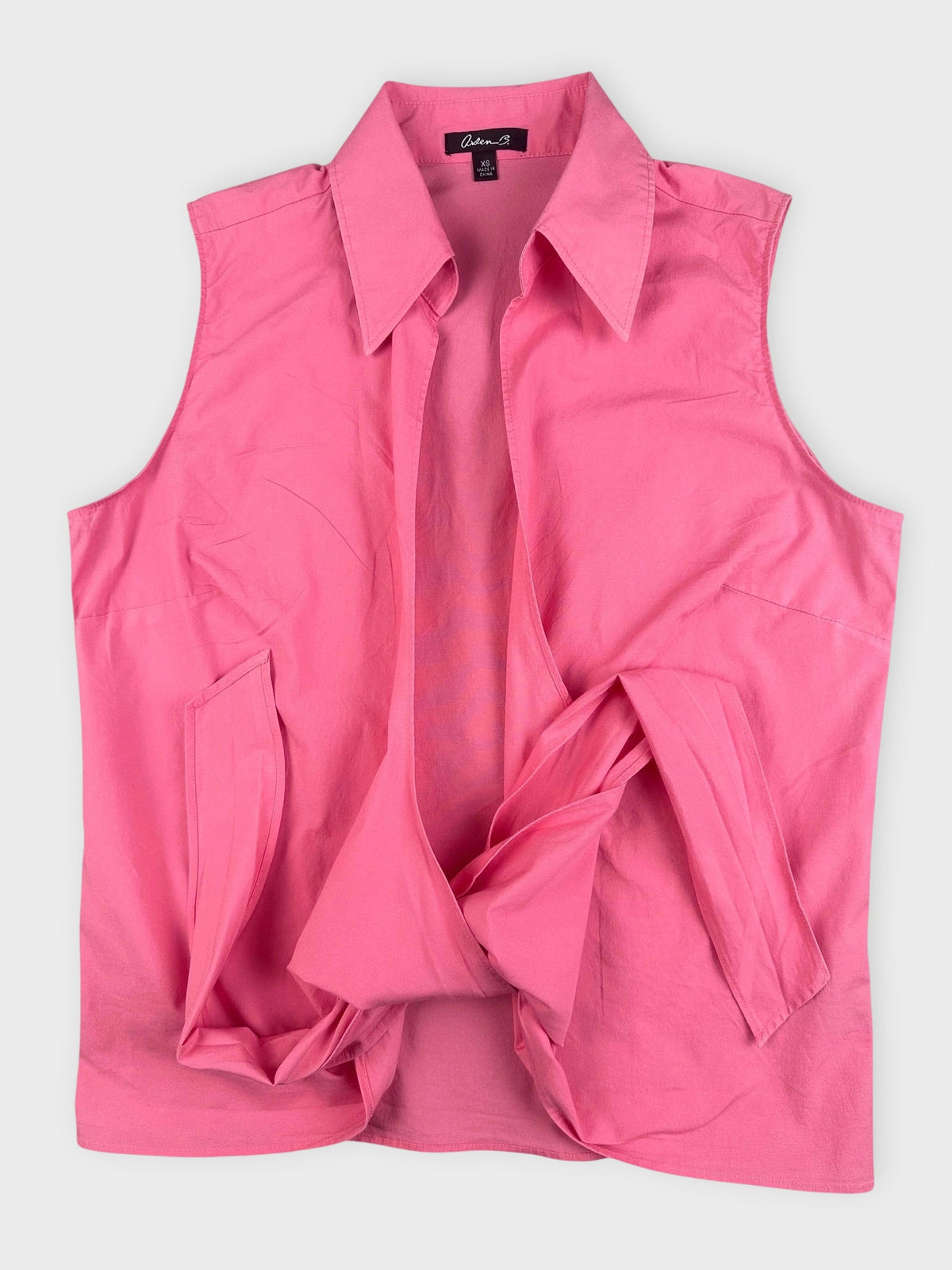 Detail view of a pink sleeveless button-down shirt with open front.