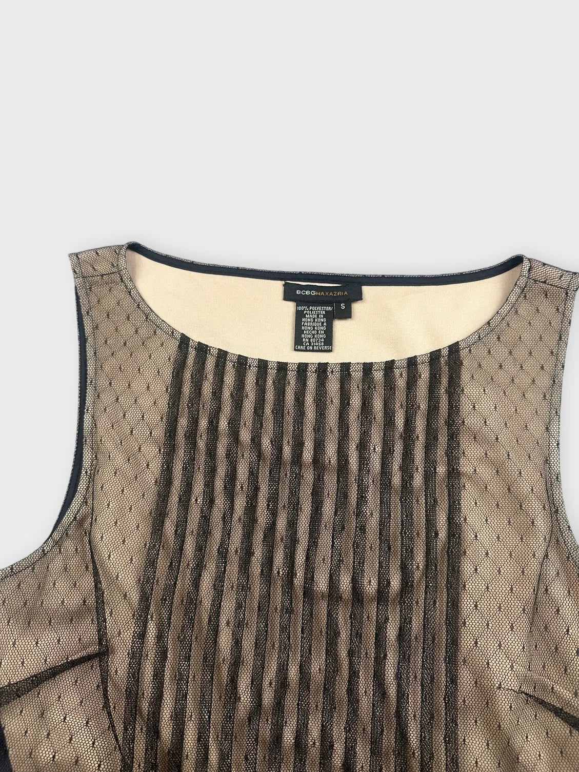 Detail view of a mesh top with pleats in tan and black.