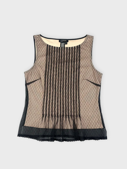 Front view of a beige mesh top with pleats and black trim.