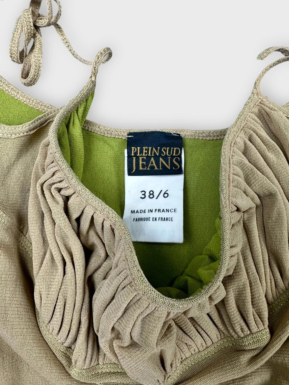 Detail view of a beige ruffled crop top with playful edges.