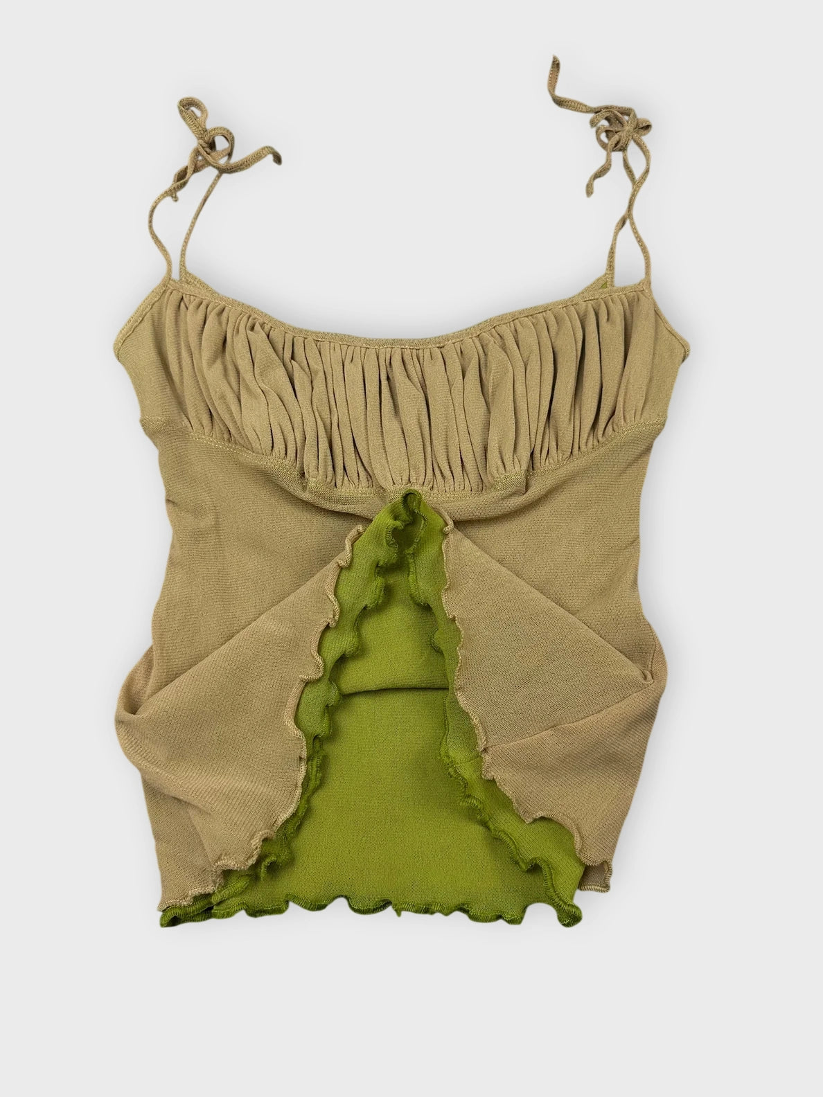 Detail view of beige ruffled crop top with playful green trim.
