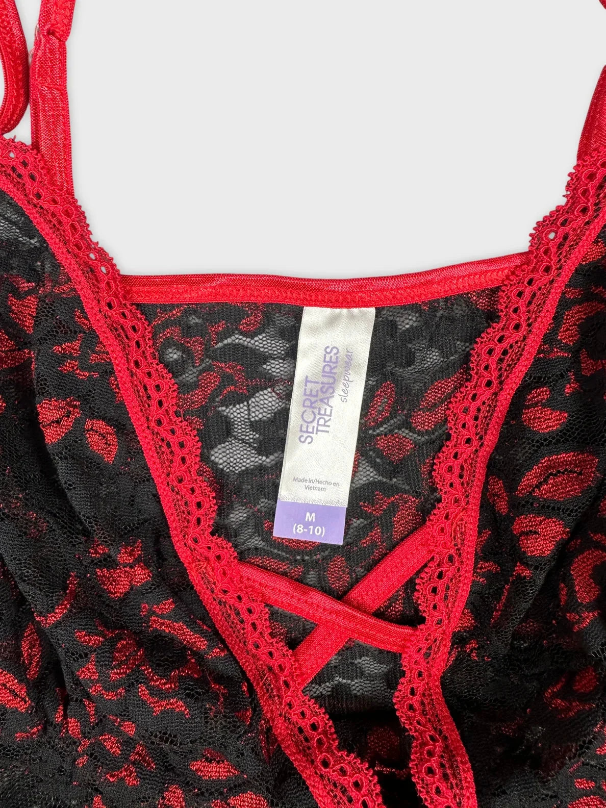 Detail view of a black floral lace top with red trim.