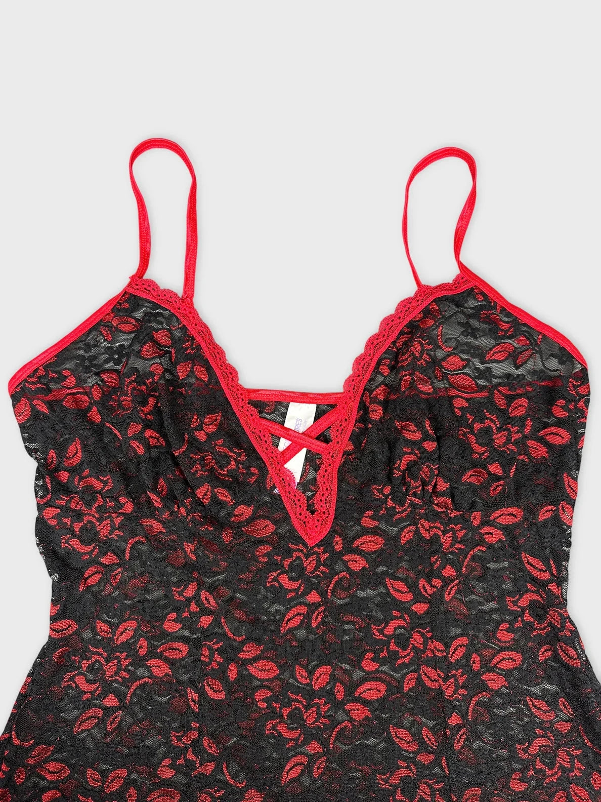 Detail view of black floral lace top with red trim and straps.
