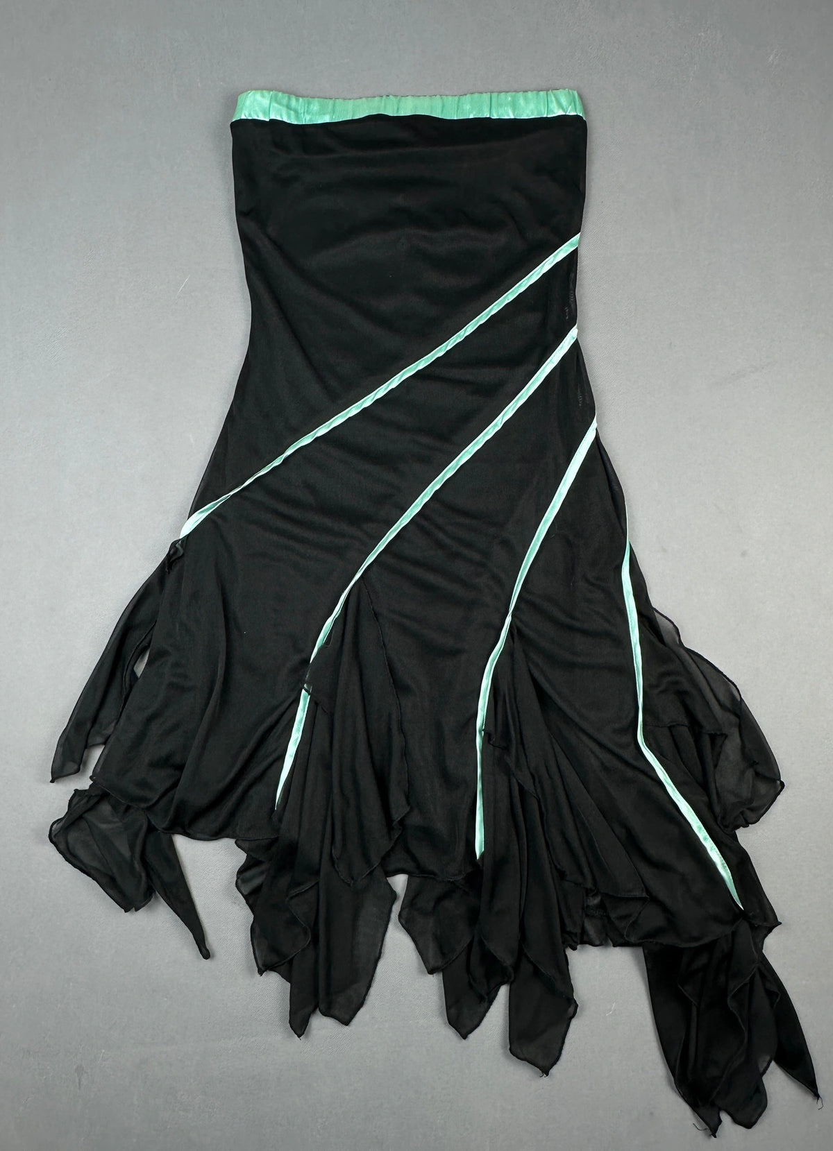 Back view of a black flowing skirt with aqua accent details and an asymmetrical silhouette.