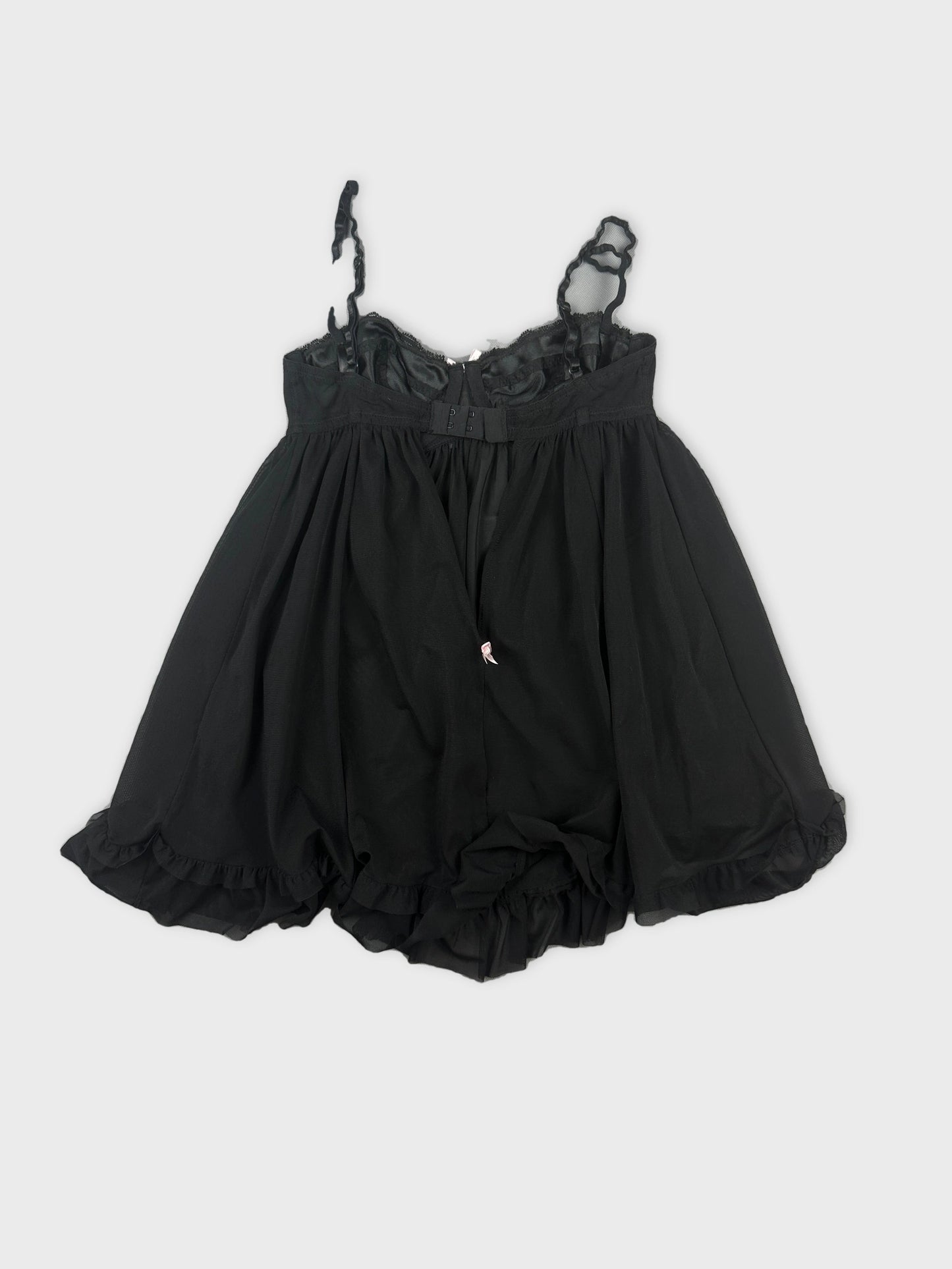 Back view of a black lace babydoll top with ruffled hemline.