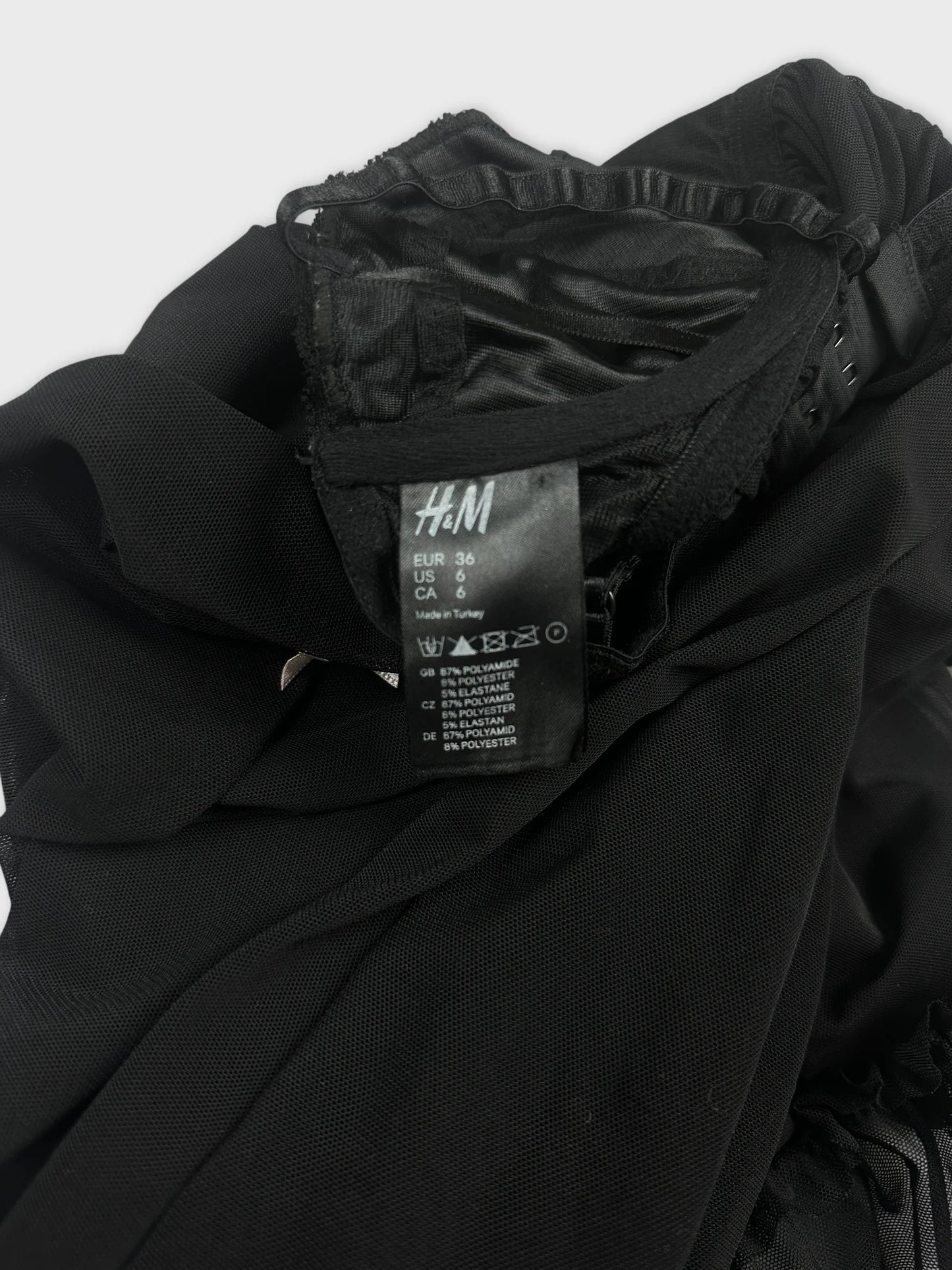 Detail view of black lace babydoll top with ruffle hem and pink bow.