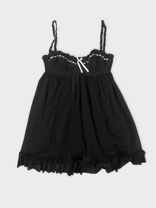 Front view of a black lace babydoll top featuring a ruffle hem and pink bow.