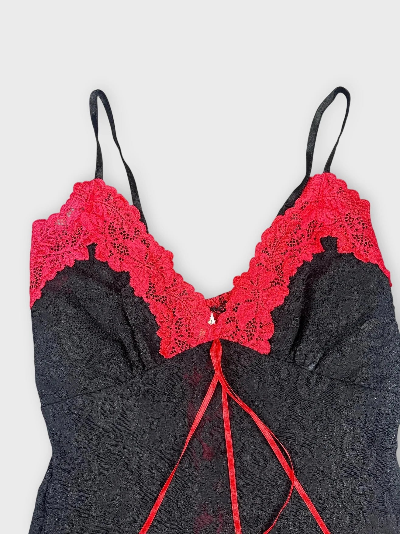 Detail view of a black lace crop top with red lace trim
