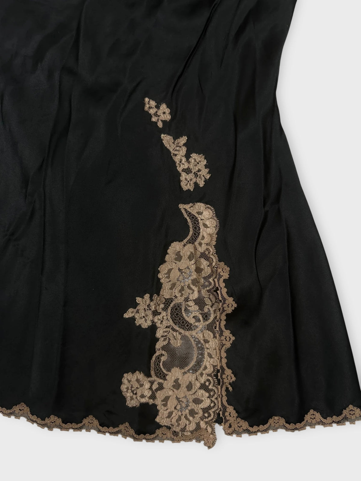Black lace trimmed cami top detail view with floral pattern embellishments.