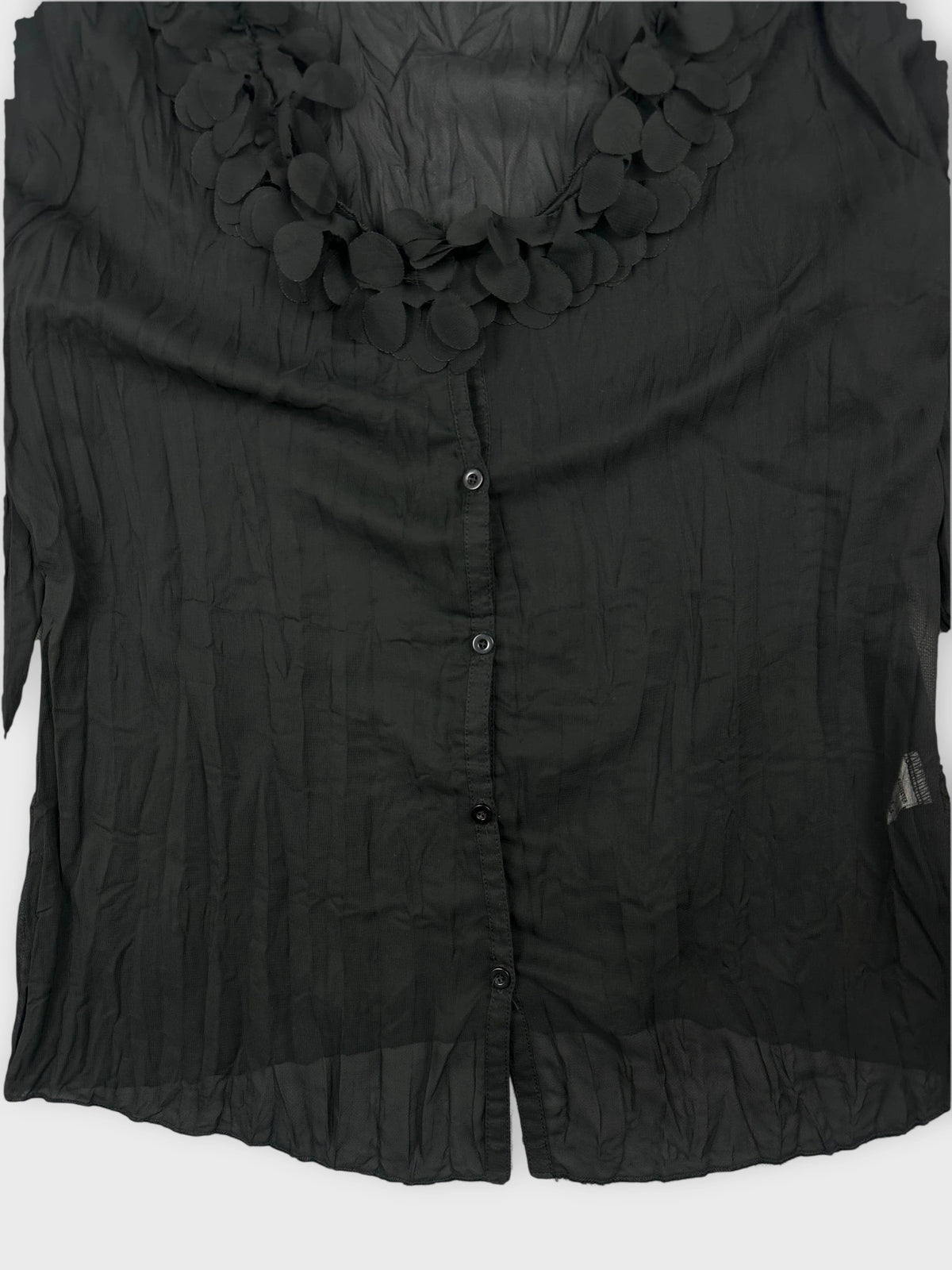 Detail view of a black long sleeve shirt with floral trim.