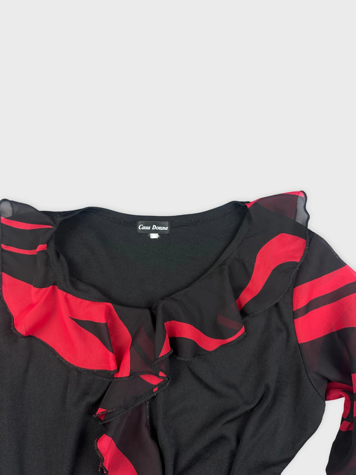 Detail view of a black and red striped top featuring a ruffled neckline.