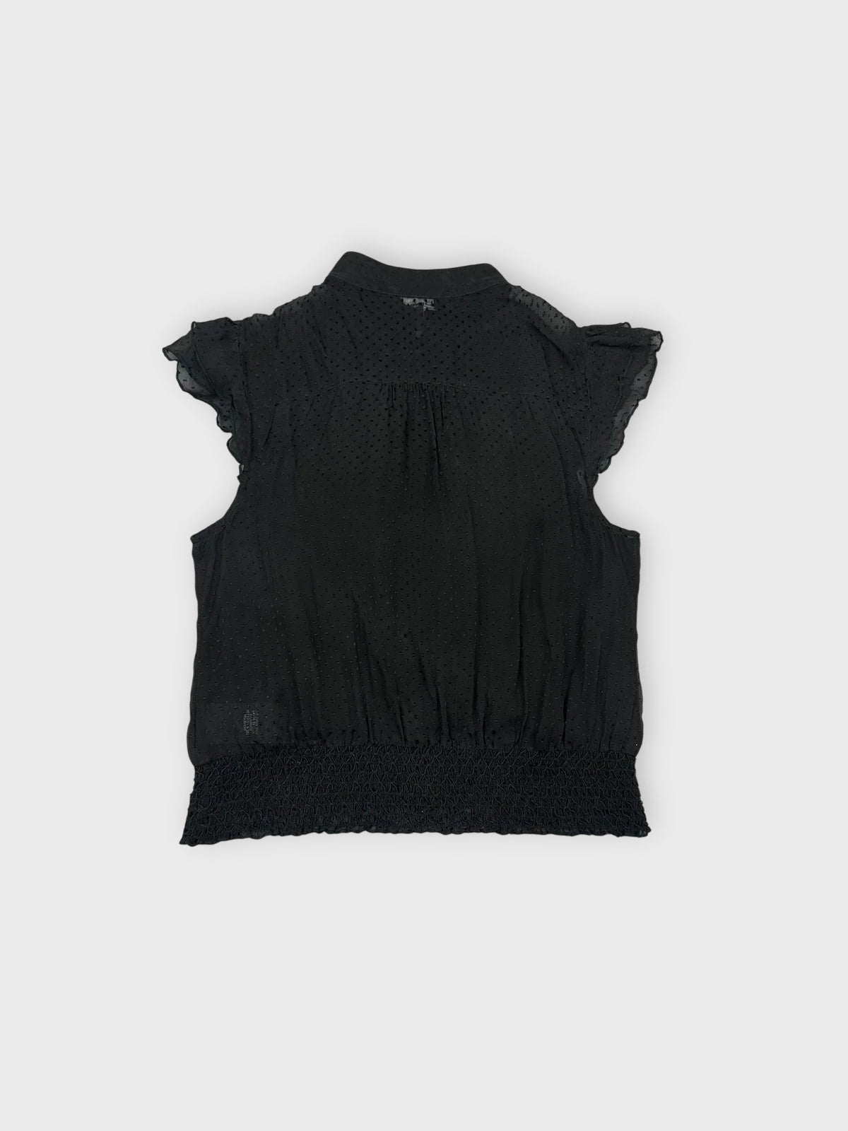Back view of a black ruffled blouse with a button detail.