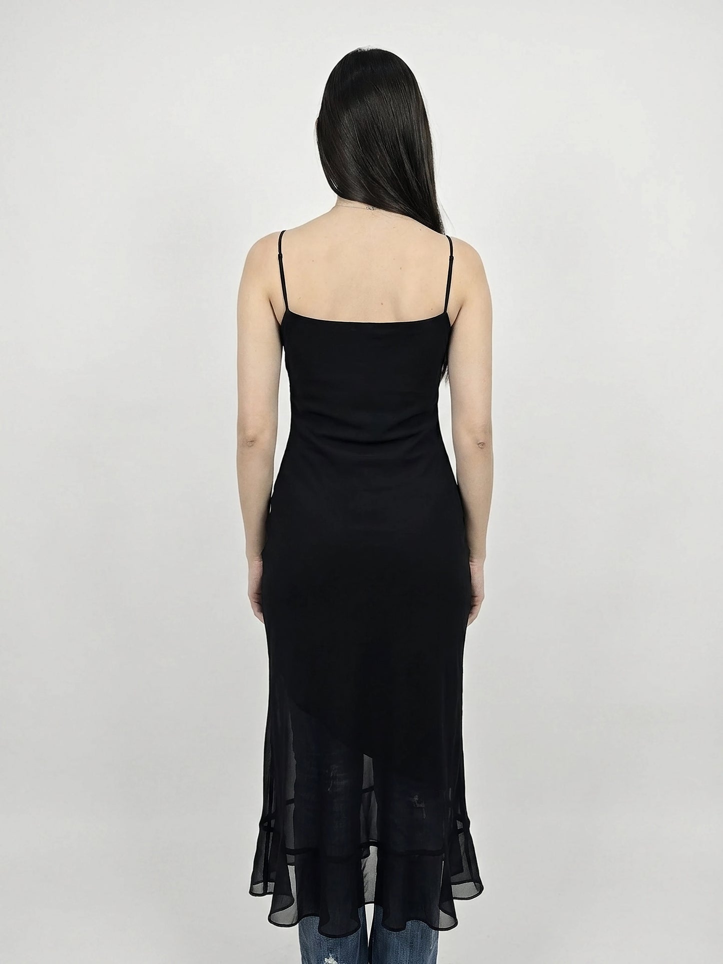 Back view of a black sheer maxi dress with a ruffle hem.