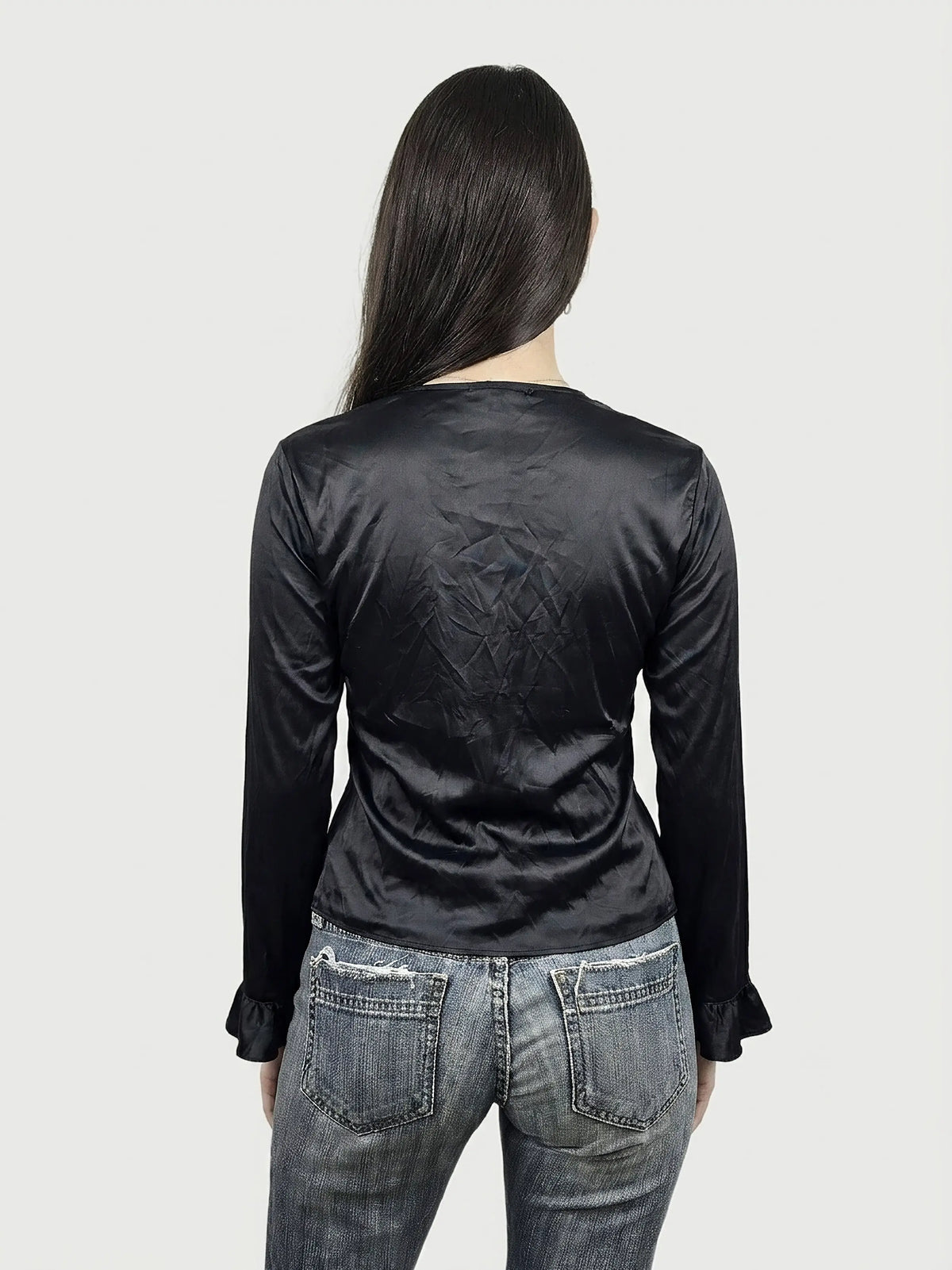 Back view of a black silk ruffled top with long sleeves.