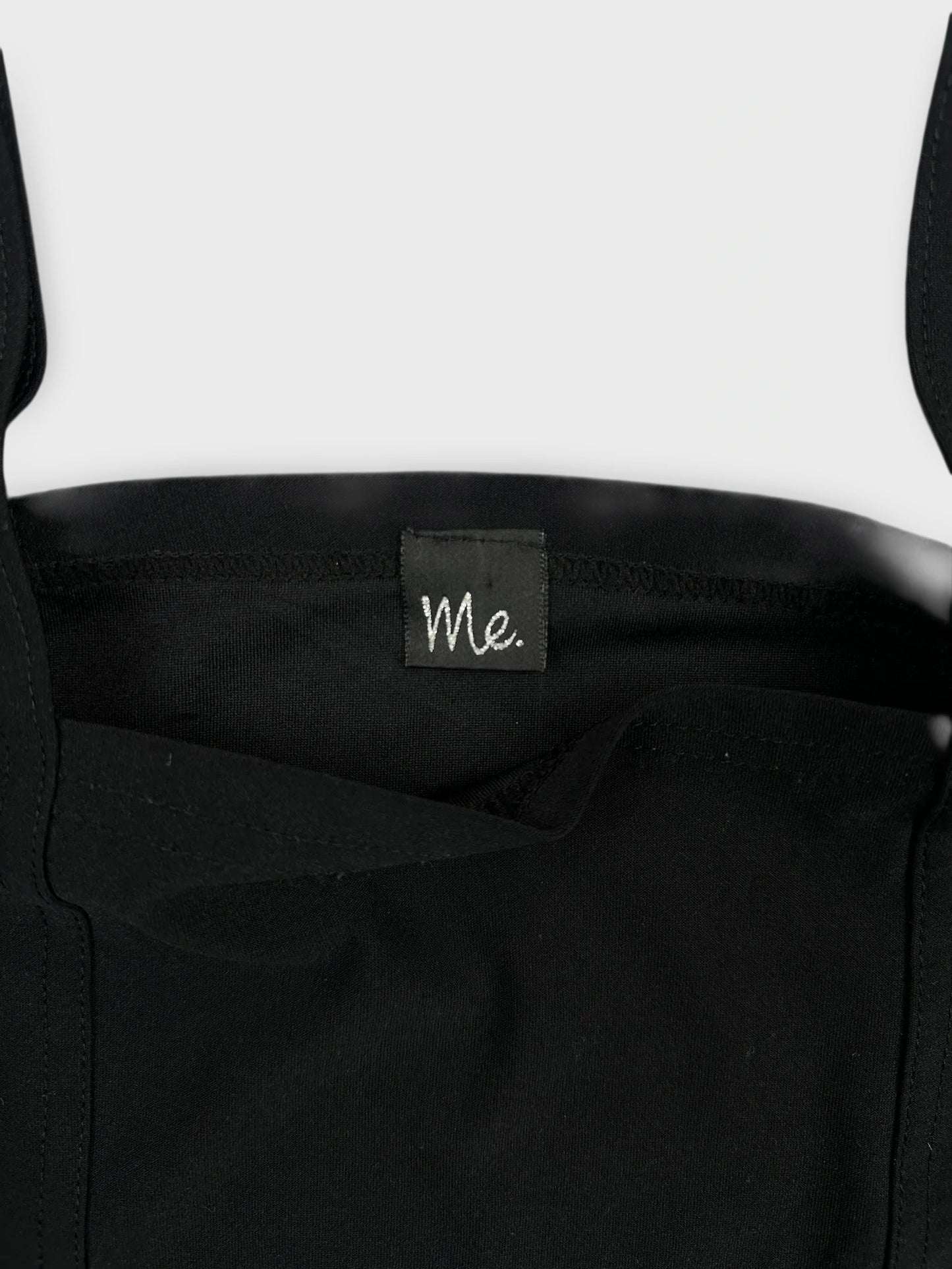 Detail view of a black sleeveless top with a square neckline.