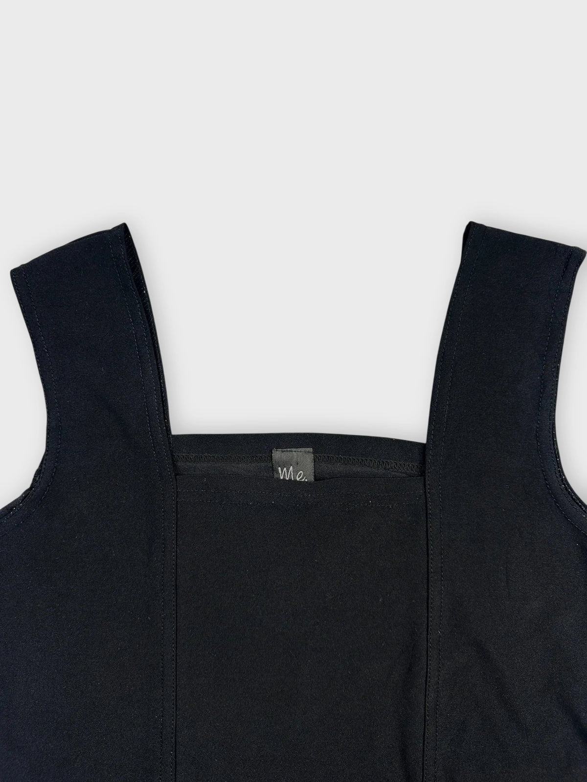Black sleeveless top detail view featuring a square neck design.