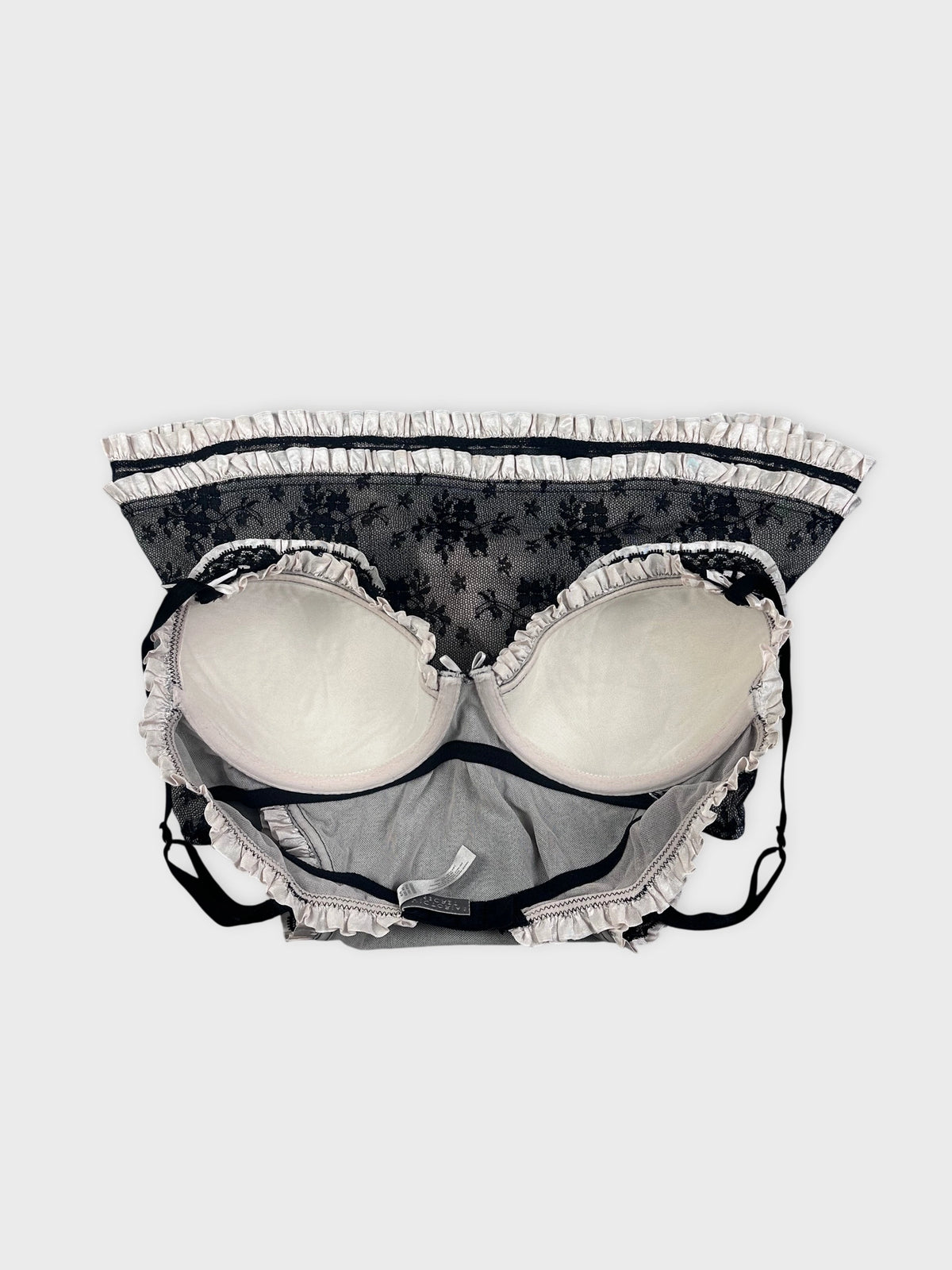 Detail view of a black lace bralette with ruffled trim.