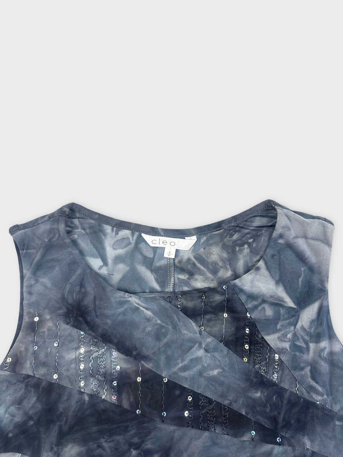 Detail view of blue tie dye sleeveless shirt with sequined embellishments.