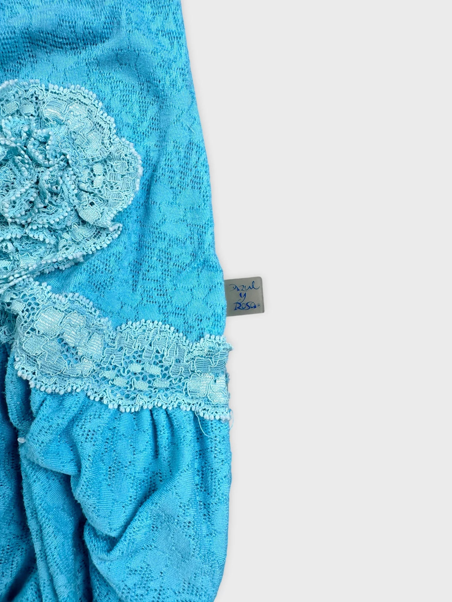 Detail view of a blue top featuring lace trim and floral design.