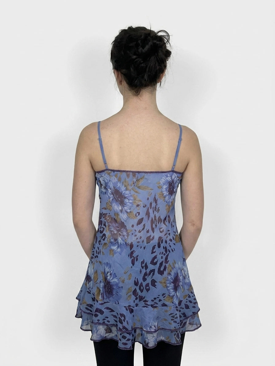 Back view of a bold floral ruffle dress in blue with layered trim.