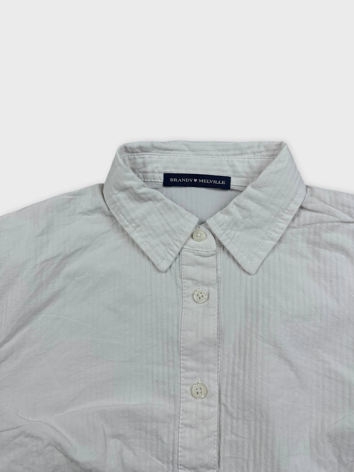 Detail view of a white button-down shirt with a striped pattern.