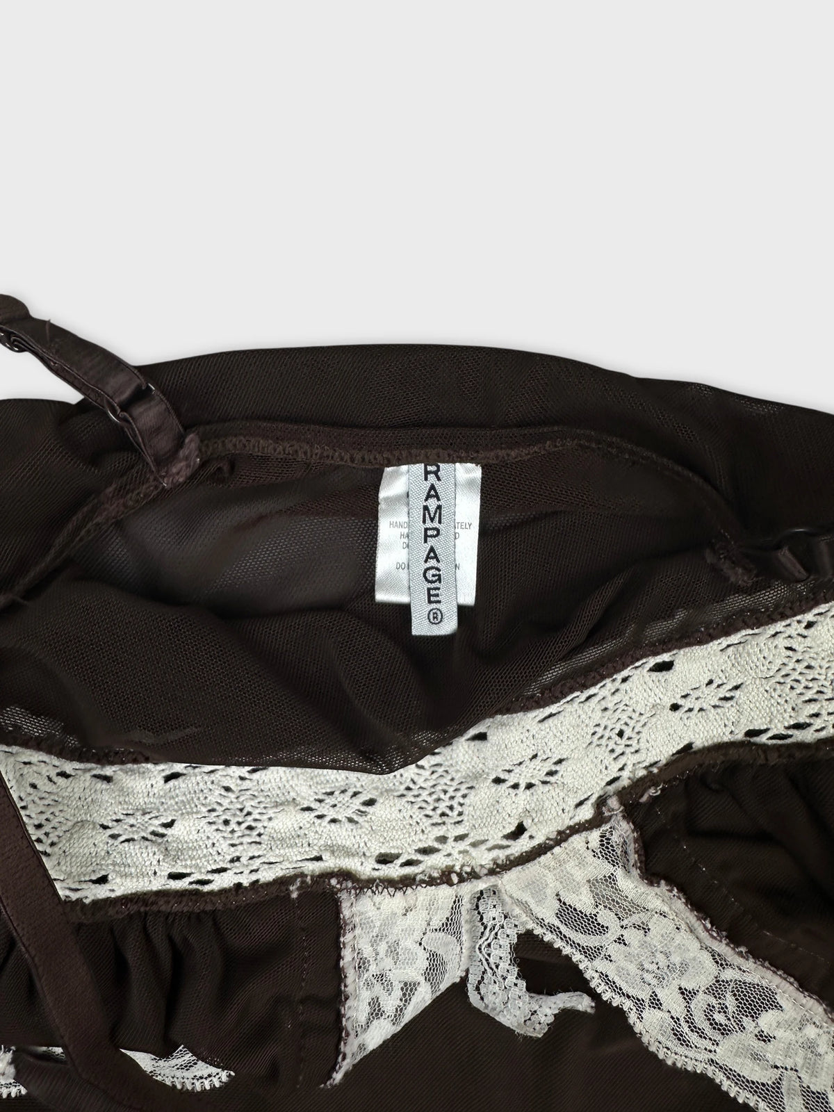 Detail view of brown mesh crop top featuring white lace trim.