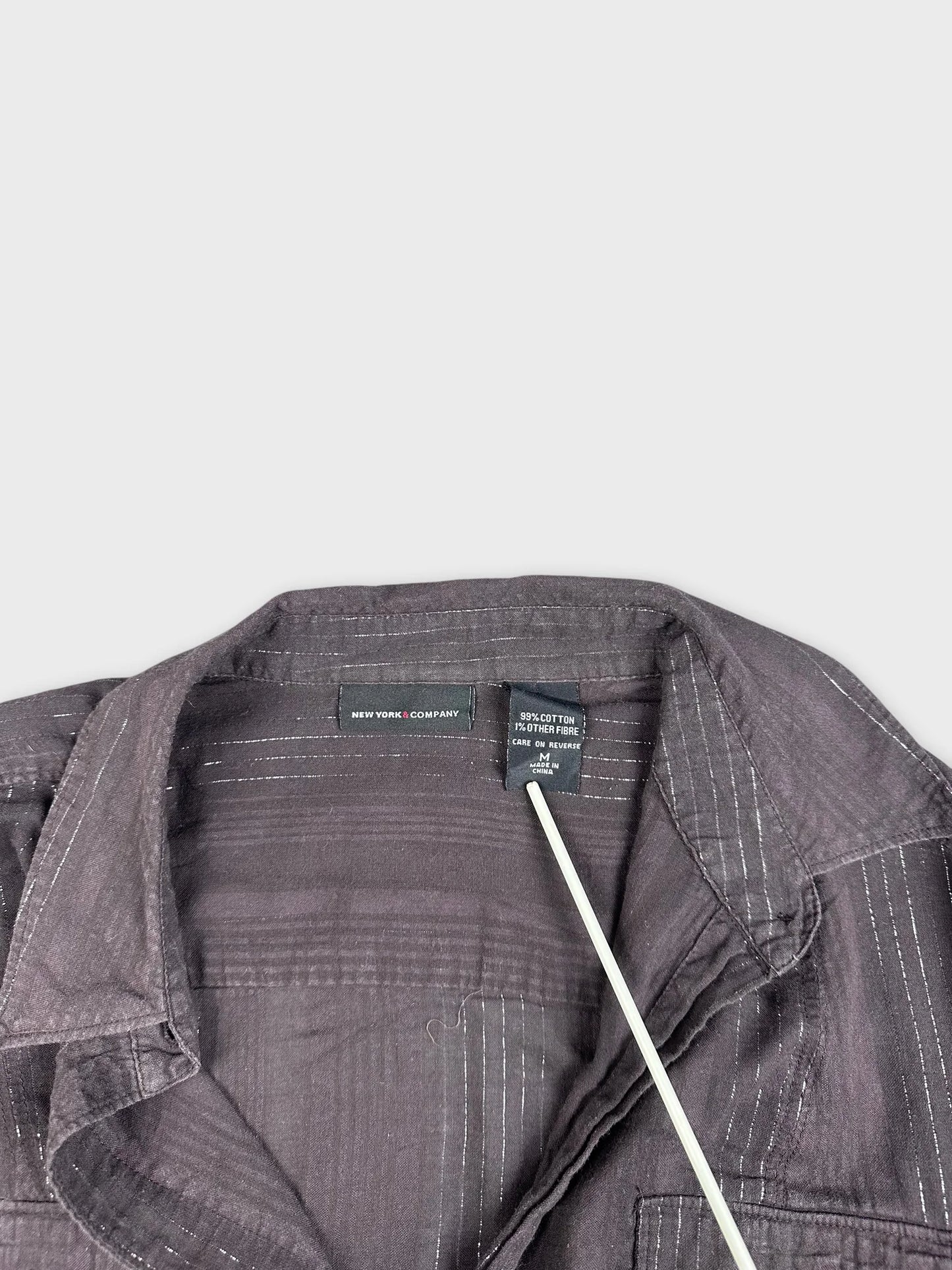 Brown striped shirt detail view featuring white stitching on collar