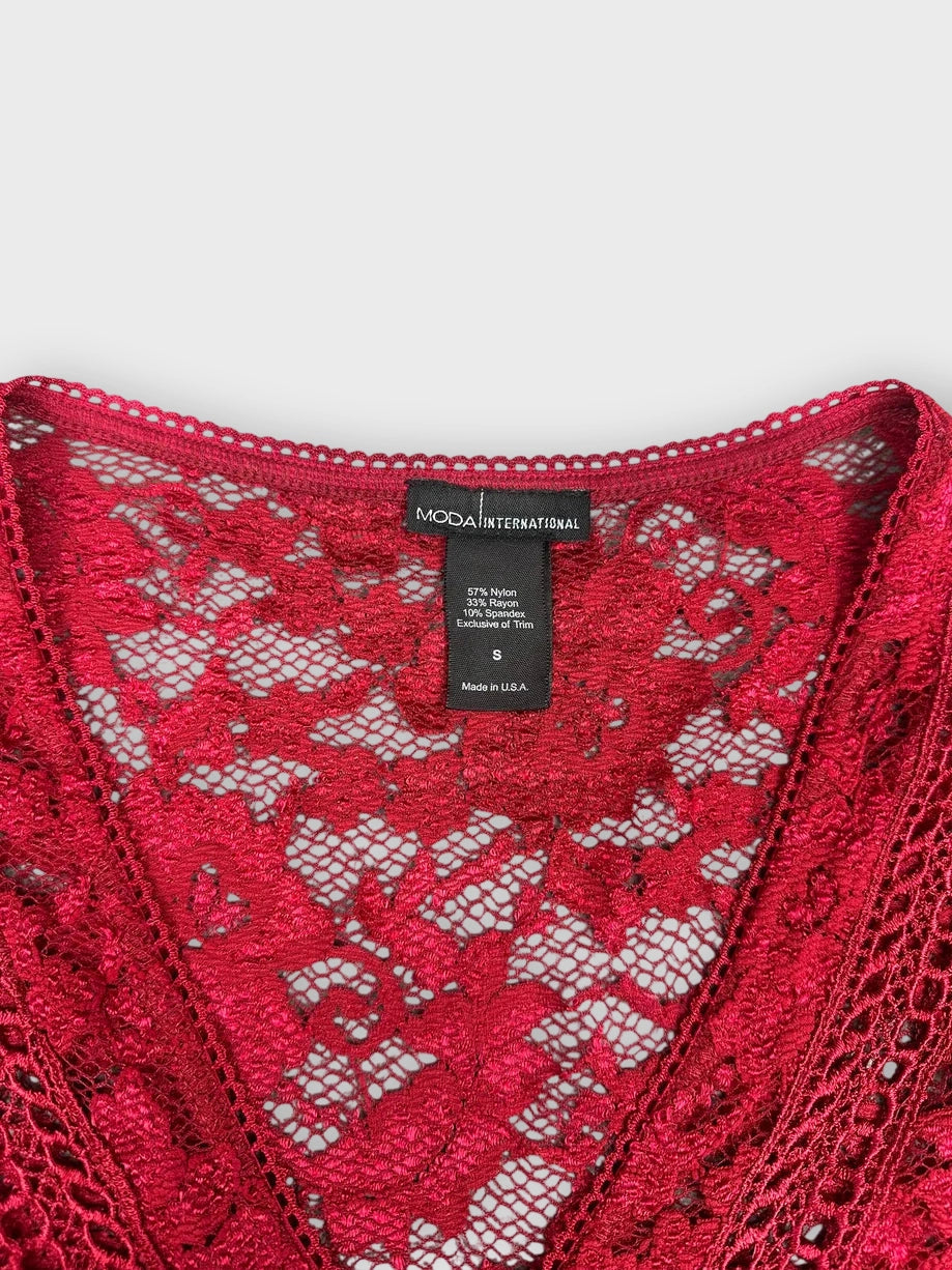 Detail view of a burgundy lace blouse showcasing a V-neckline and intricate floral pattern.
