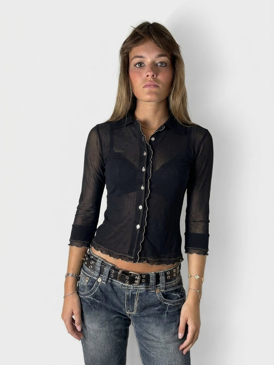 Chic black collared shirt with ruffled hem, front view, featuring a sheer material.