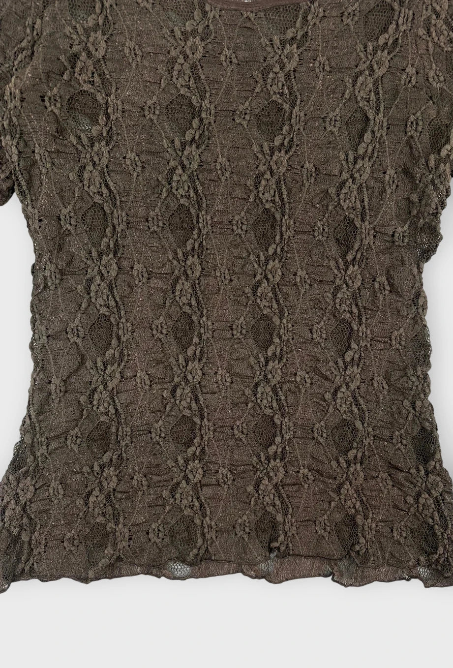 Detail view of a chic black lace top with short sleeves and intricate lace pattern.