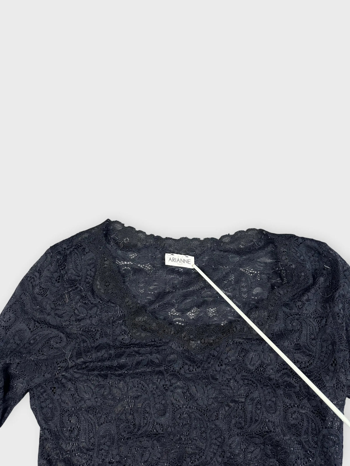 Detail view of a black lace top featuring a scalloped neckline.