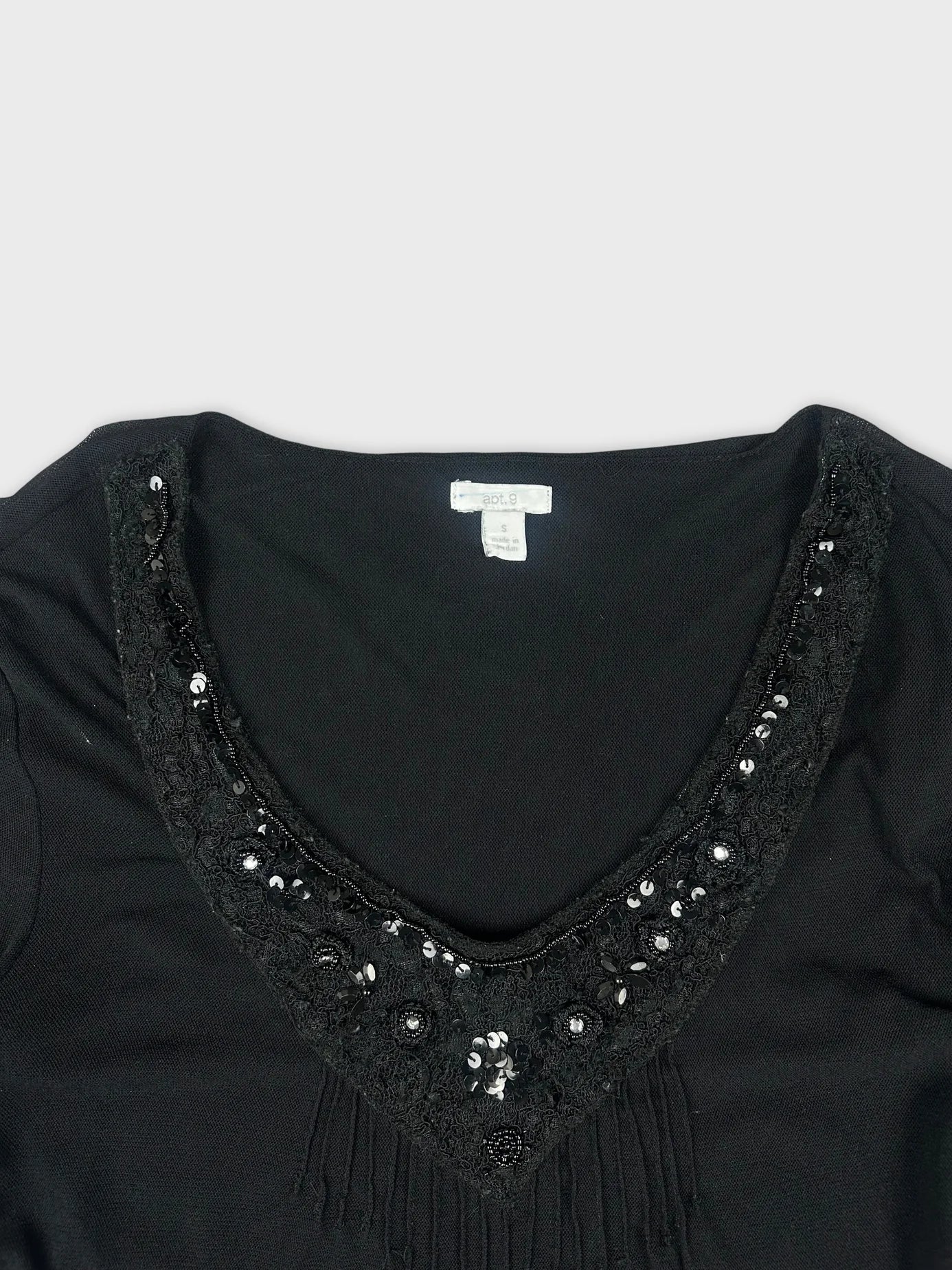 Detail view of a chic black sheer top with embellished neckline and lace trim.
