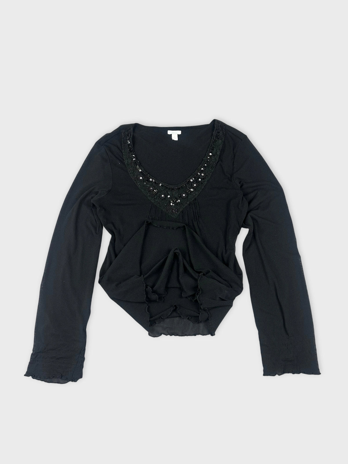 Detail view of a black sheer top with embellished neckline.