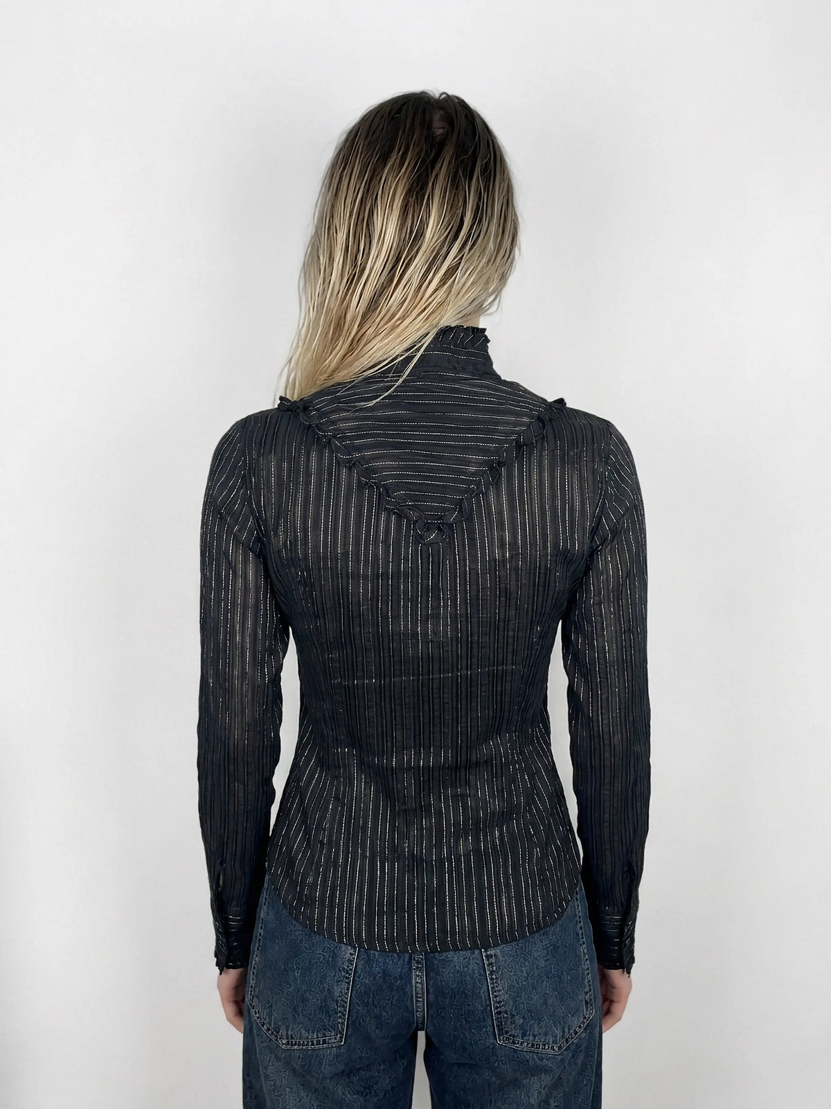 Back view of a black striped blouse featuring ruffled neckline detail.