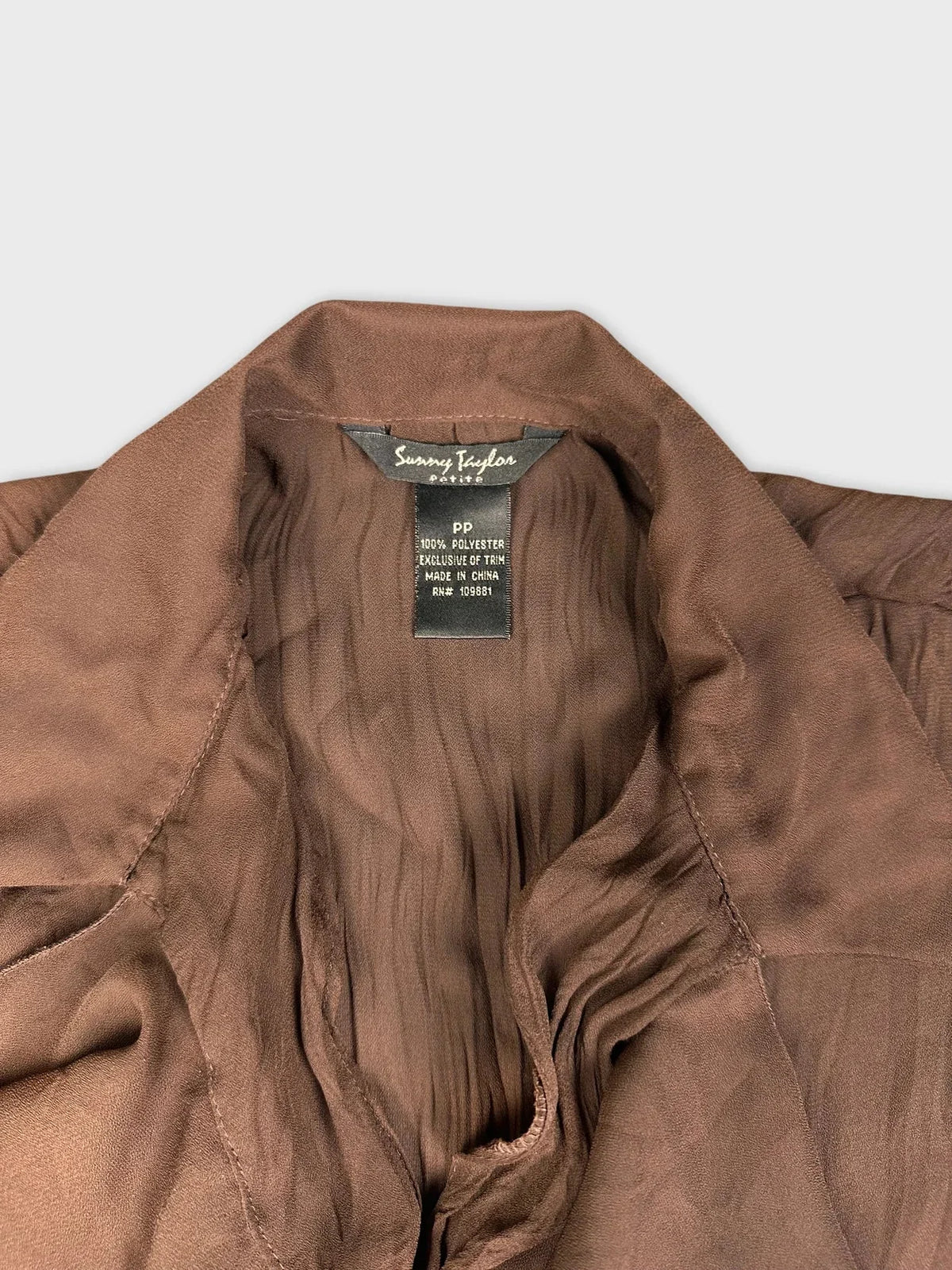 Detail view of a chic brown blouse featuring ruffle and lace details.