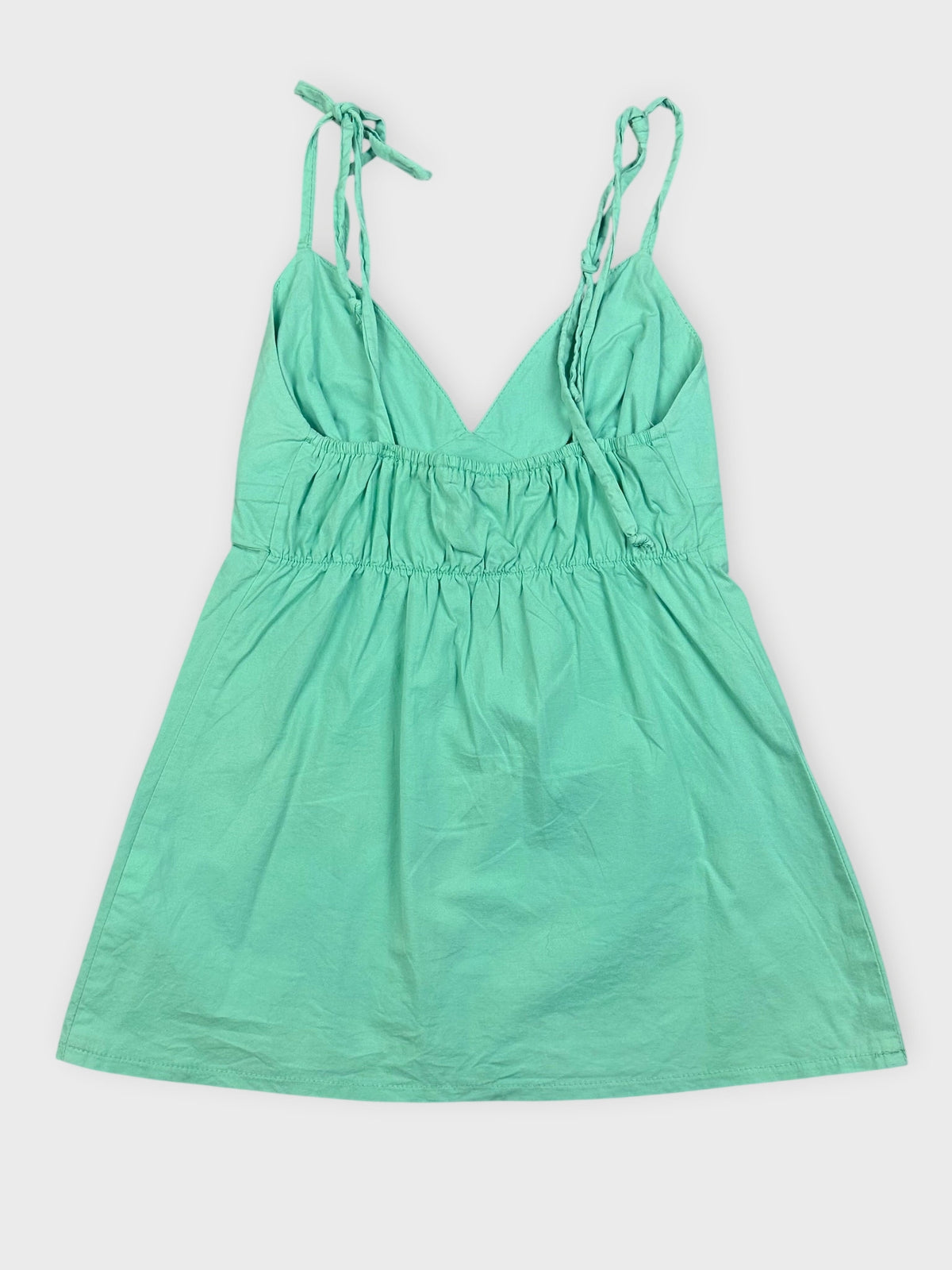 Back view of a mint green mini dress with adjustable straps and a V-neck design.