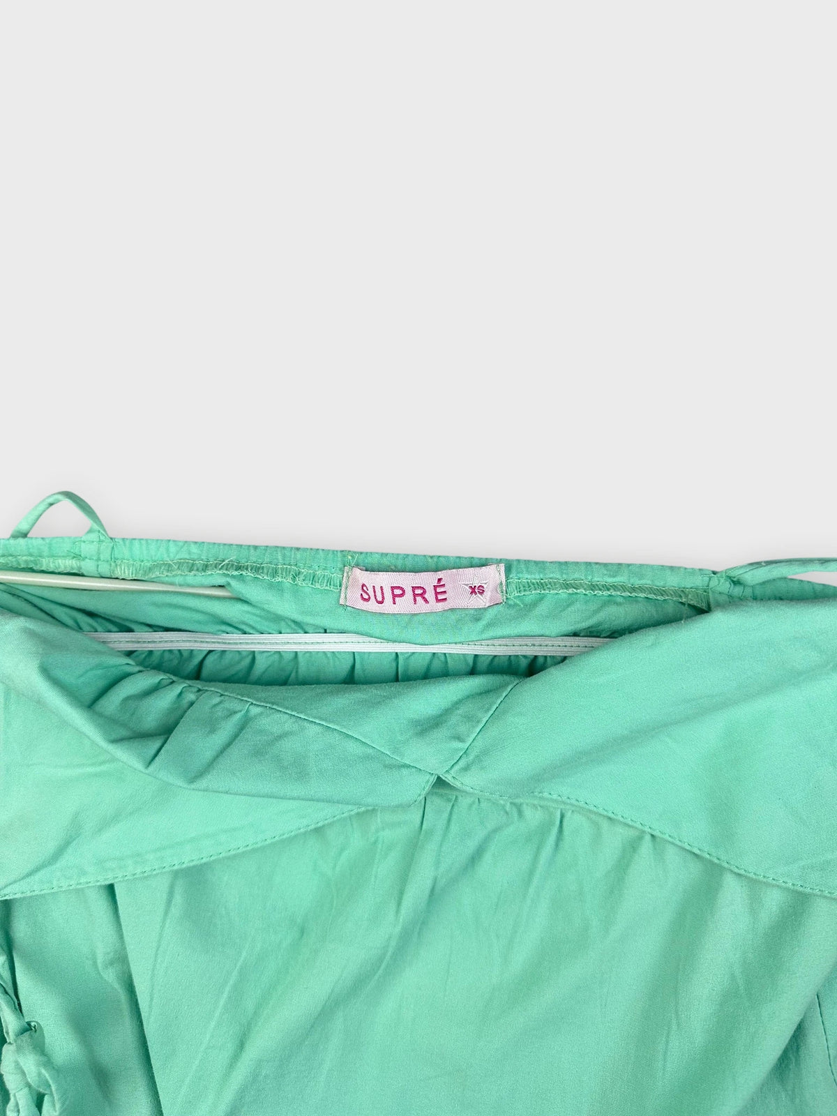 Detail view of a mint green mini dress with adjustable straps.