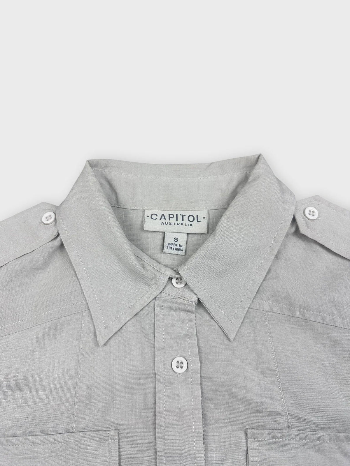 detail view of light beige button-up top with two front pockets and buttons