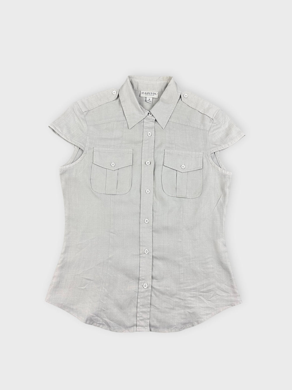 Front view of light beige button-up top with short sleeves and pocket detail.