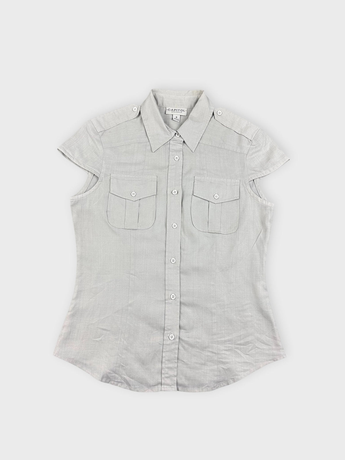 Front view of light beige button-up top with short sleeves and pocket detail.