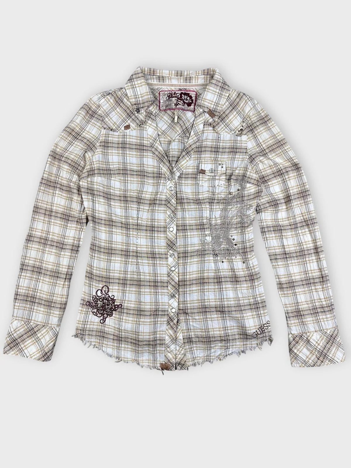 Detail view of plaid button-up shirt in beige with frayed hem.