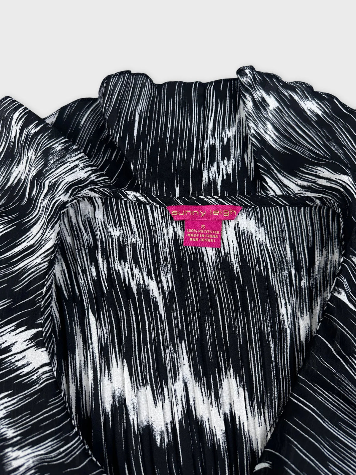 Detail view of black and white plissé top with ruffled shoulder detail.