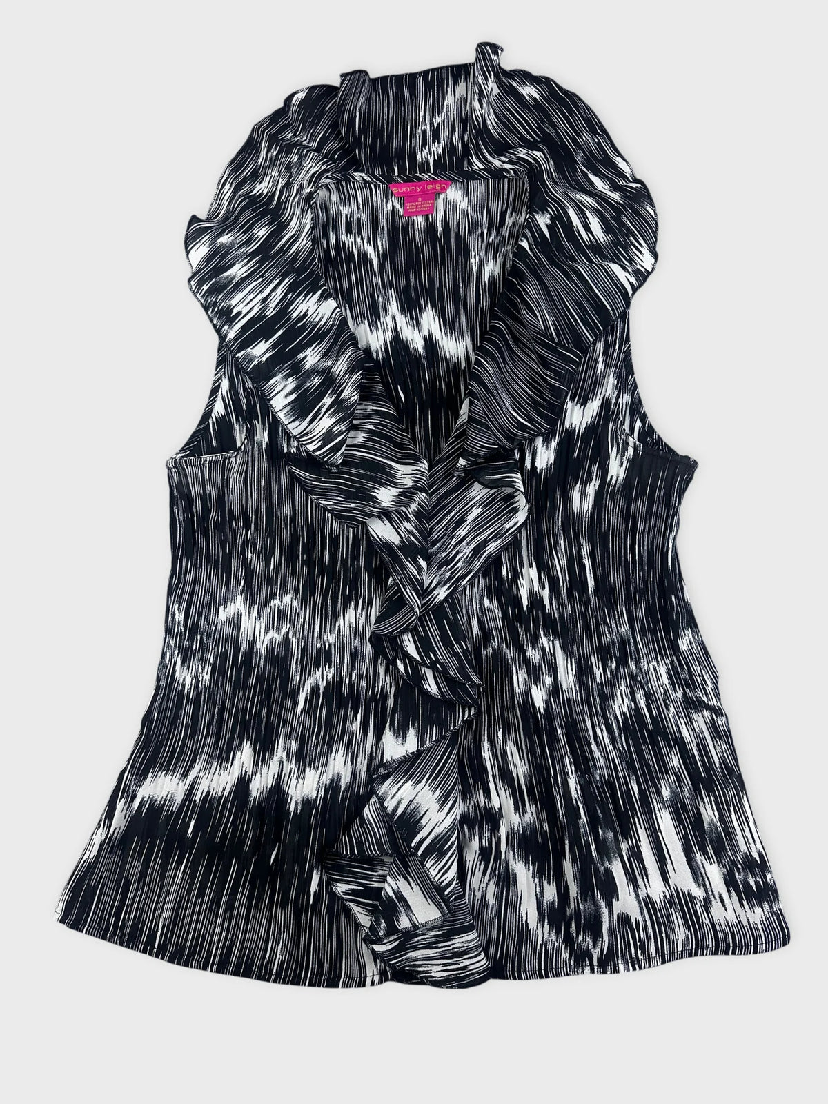 Detail view of a black and white plissé top with ruffled collar