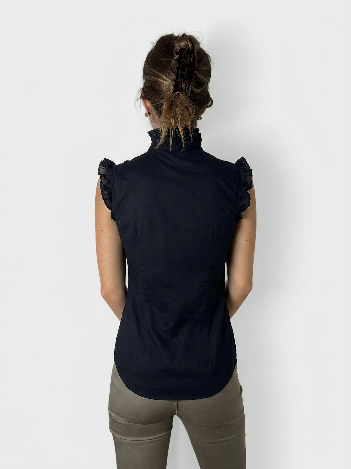 Back view of a black ruffled cotton top with a high collar.