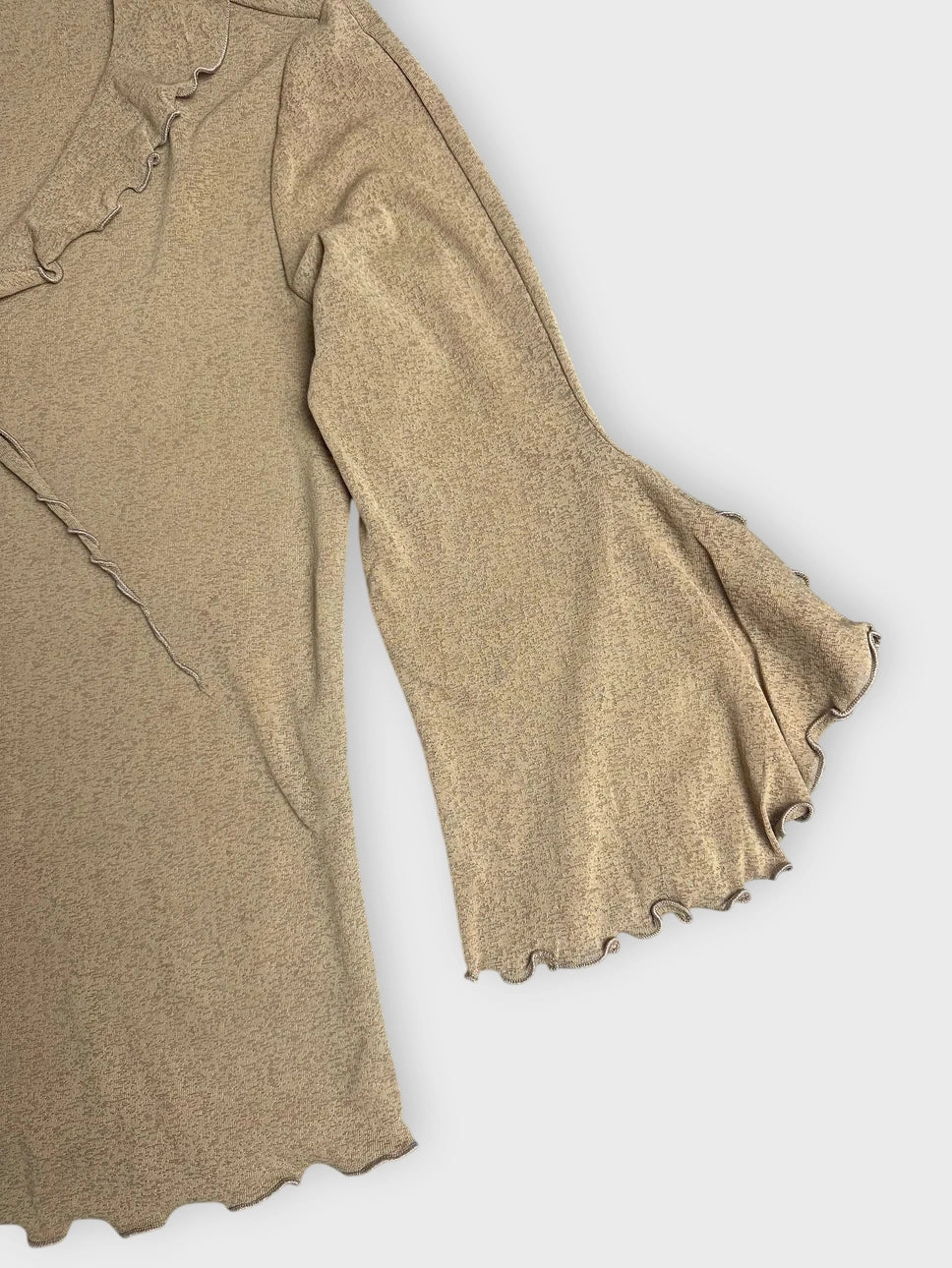 Detail view of a chic ruffled long sleeve top in warm beige color