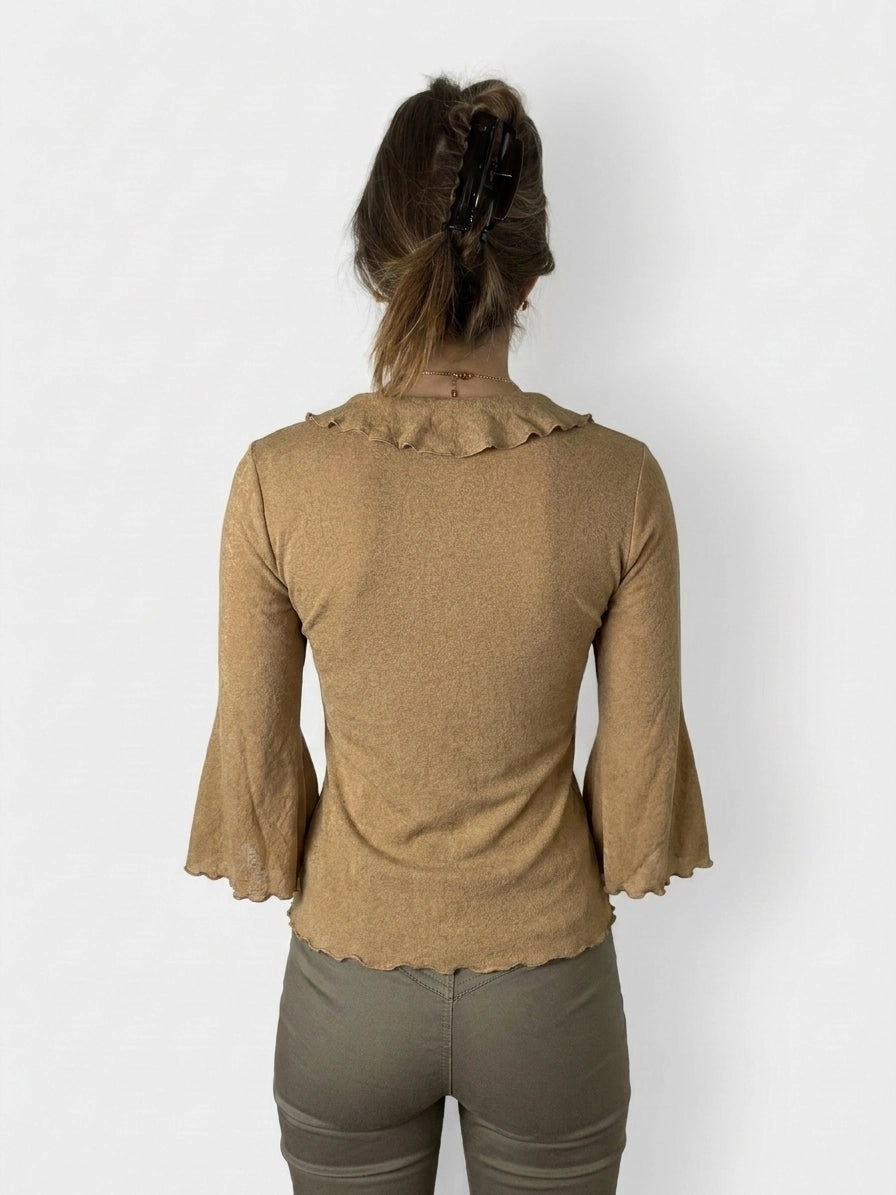 Back view of a warm beige long sleeve top with ruffled trim.