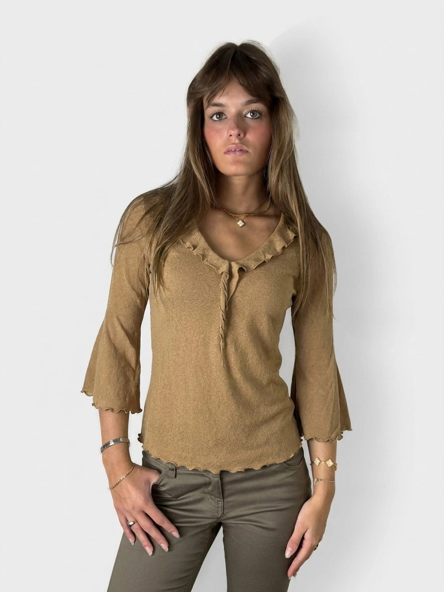 Front view of a long sleeve top in warm beige with ruffled trim.