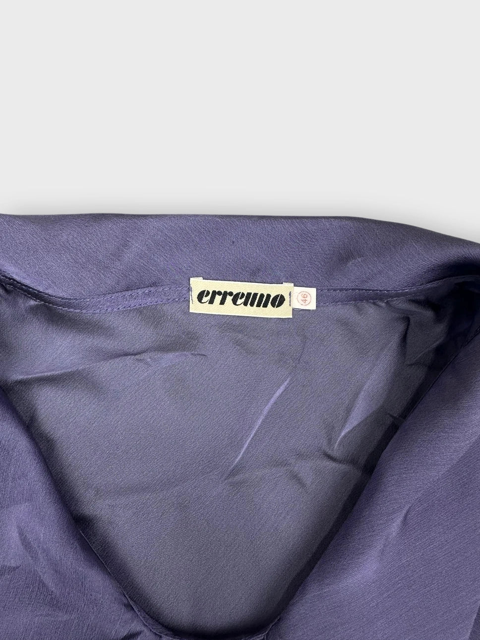 Detail view of a chic sheer purple top featuring draped detail.