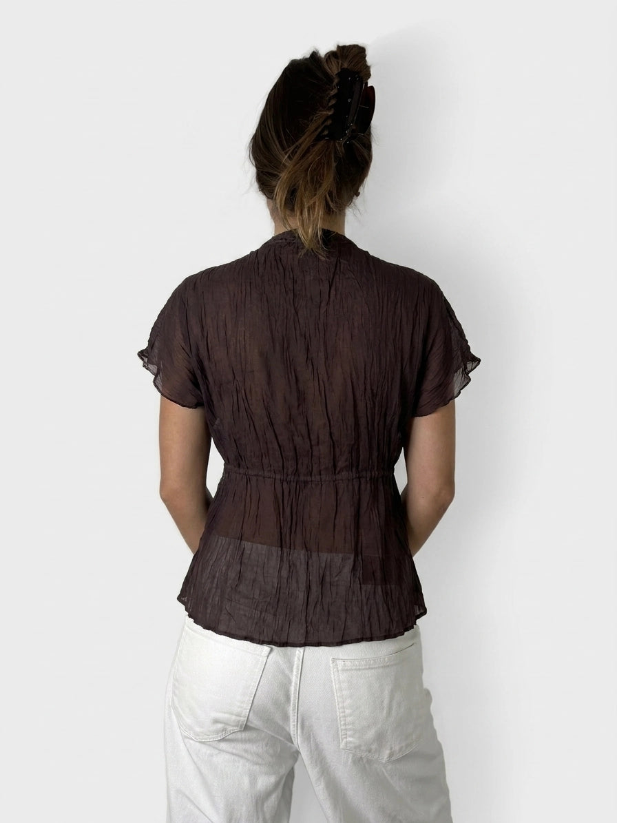 Back view of a sheer brown ruffled top with tie detail.
